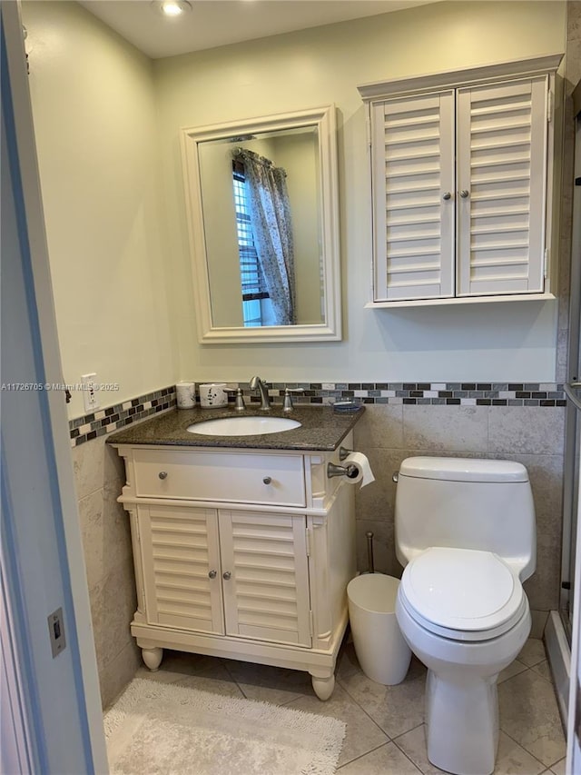 bathroom with tile walls, tile patterned floors, vanity, and toilet