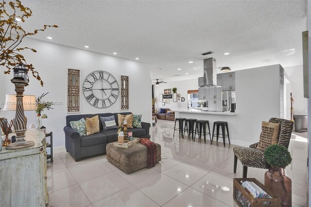 tiled living room featuring ceiling fan, sink, and a textured ceiling