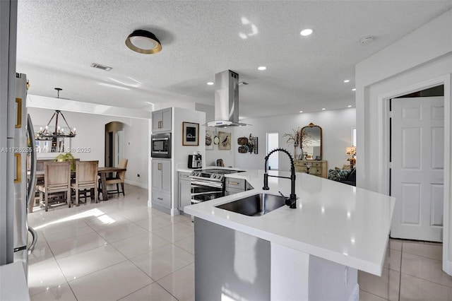 kitchen with pendant lighting, sink, island exhaust hood, light tile patterned flooring, and stainless steel appliances