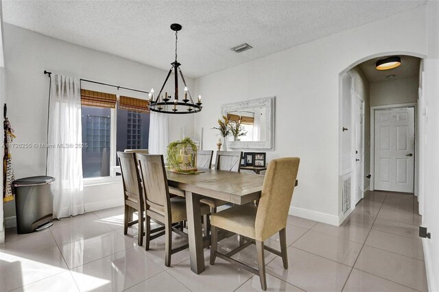 tiled dining area featuring a notable chandelier, a wealth of natural light, and a textured ceiling