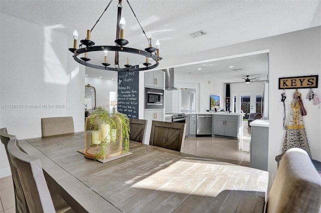 dining area with ceiling fan with notable chandelier, a textured ceiling, and light tile patterned flooring