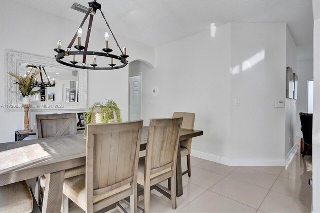 tiled dining room with a chandelier