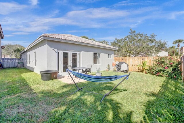 rear view of house featuring french doors and a lawn