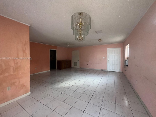 spare room with a textured ceiling, a notable chandelier, and light tile patterned floors