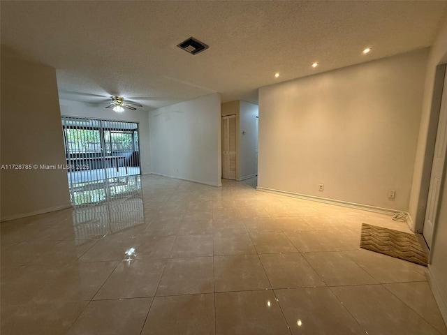 empty room featuring tile patterned floors, ceiling fan, and a textured ceiling