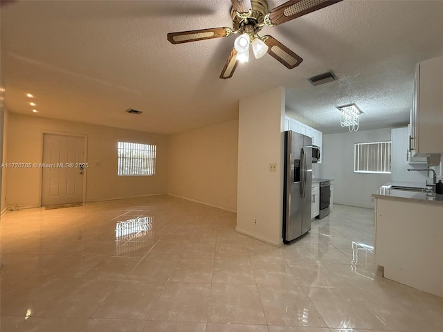 unfurnished living room with sink, a textured ceiling, ceiling fan, and light tile patterned floors