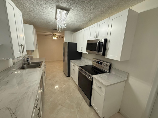 kitchen featuring sink, stainless steel appliances, white cabinetry, and light stone countertops