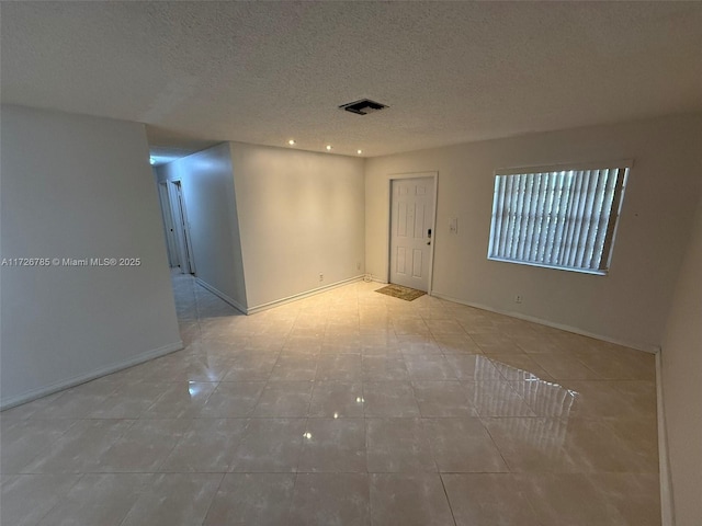 tiled spare room with a textured ceiling