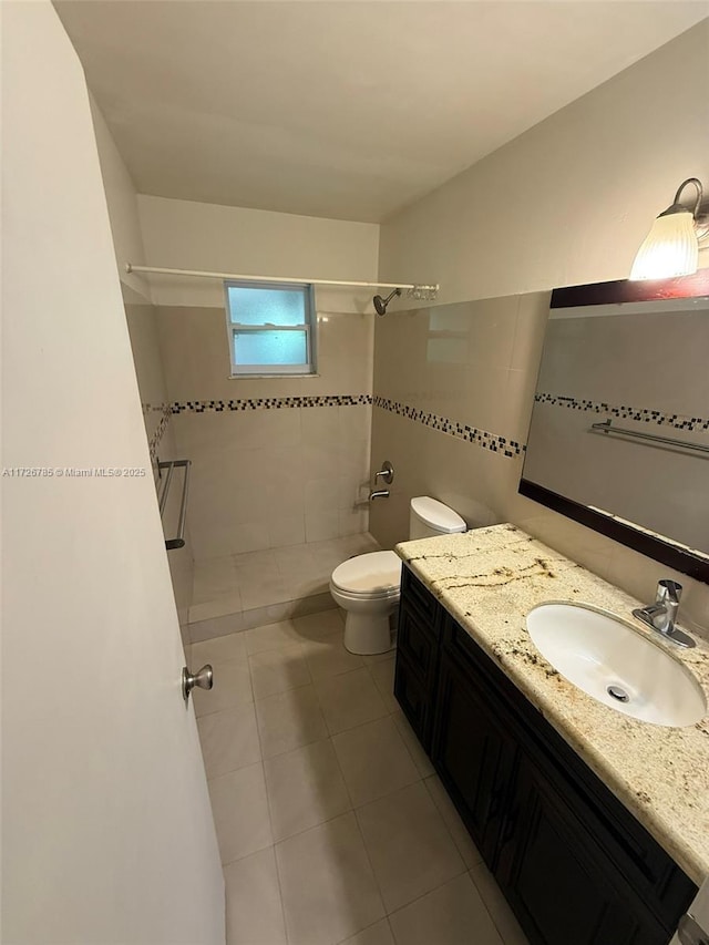 bathroom featuring tile patterned floors, a tile shower, vanity, and toilet