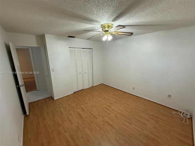 unfurnished bedroom with a textured ceiling, a closet, ceiling fan, and hardwood / wood-style flooring