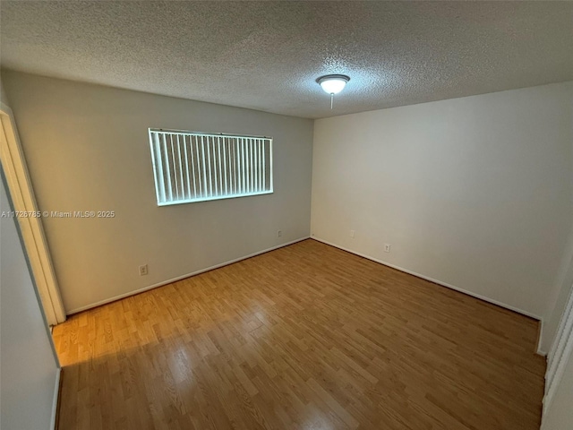 empty room featuring a textured ceiling and hardwood / wood-style flooring