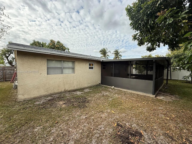 rear view of house featuring a yard and a sunroom