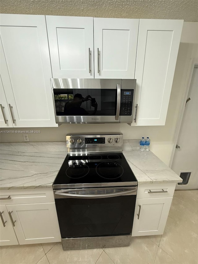 kitchen featuring stainless steel appliances, white cabinets, and light stone countertops