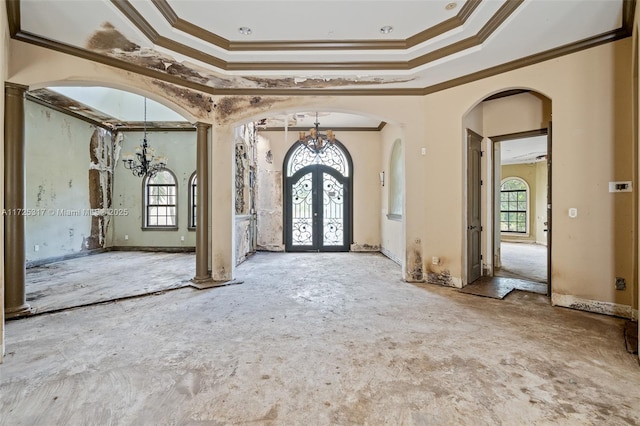 foyer entrance featuring a high ceiling, french doors, crown molding, and a chandelier