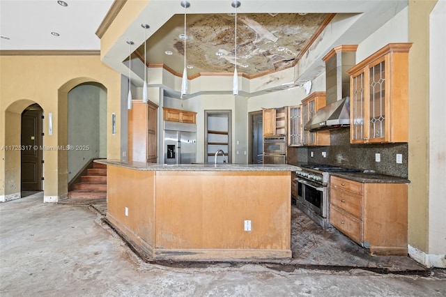 kitchen with decorative light fixtures, tasteful backsplash, an island with sink, high end appliances, and wall chimney range hood