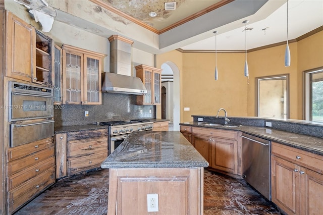 kitchen featuring stainless steel appliances, pendant lighting, decorative backsplash, wall chimney exhaust hood, and sink