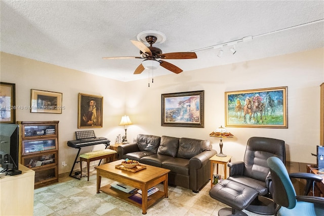 living room with a textured ceiling, rail lighting, and ceiling fan