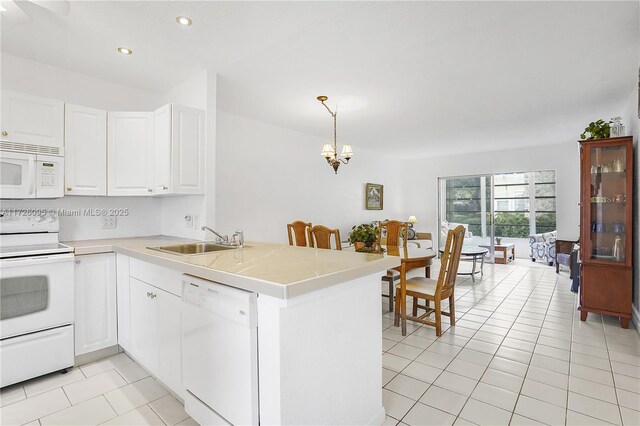 kitchen featuring white appliances, kitchen peninsula, white cabinets, decorative light fixtures, and sink