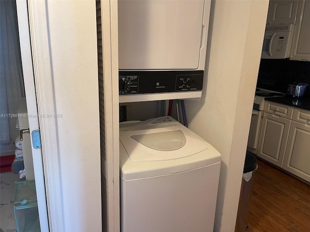 washroom with water heater, dark hardwood / wood-style floors, and stacked washer and clothes dryer