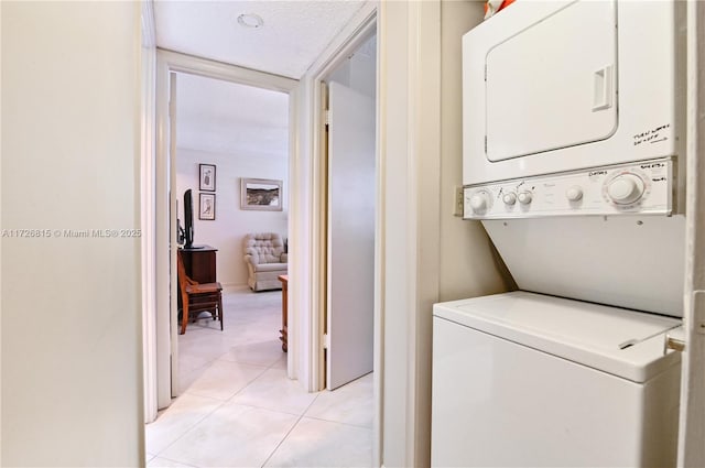 laundry room featuring a textured ceiling, light tile patterned floors, and stacked washer / dryer