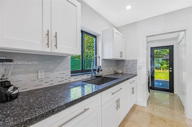 kitchen featuring sink, white cabinets, dark stone counters, and a healthy amount of sunlight