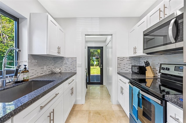 kitchen with dark stone countertops, white cabinetry, and appliances with stainless steel finishes