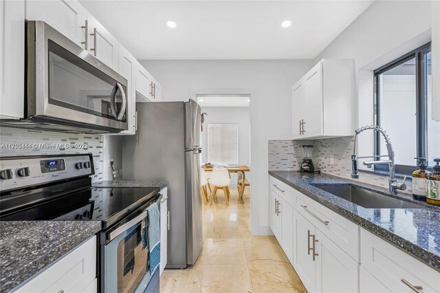 kitchen featuring sink, white cabinetry, dark stone counters, and appliances with stainless steel finishes