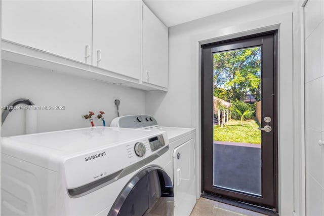 clothes washing area featuring cabinets and washing machine and dryer