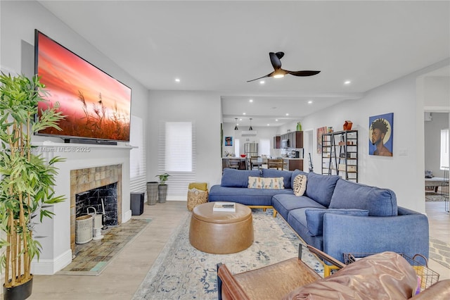 living room with ceiling fan, light hardwood / wood-style flooring, a wealth of natural light, and a fireplace