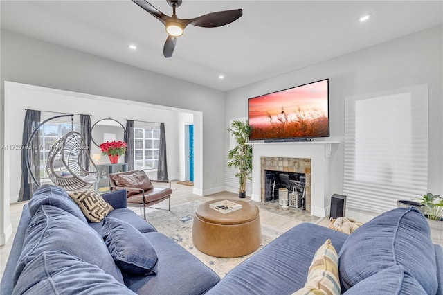 living room with ceiling fan, light hardwood / wood-style flooring, and a tile fireplace