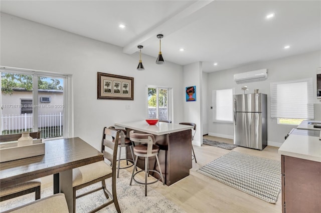 kitchen with decorative light fixtures, a kitchen bar, light hardwood / wood-style floors, stainless steel fridge, and a wall unit AC