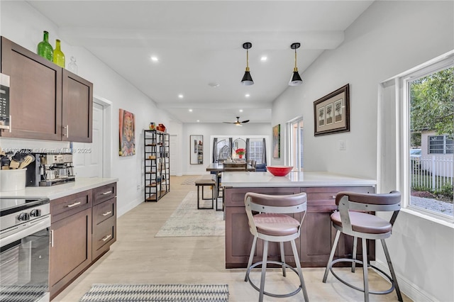 kitchen with appliances with stainless steel finishes, hanging light fixtures, a healthy amount of sunlight, and a kitchen bar