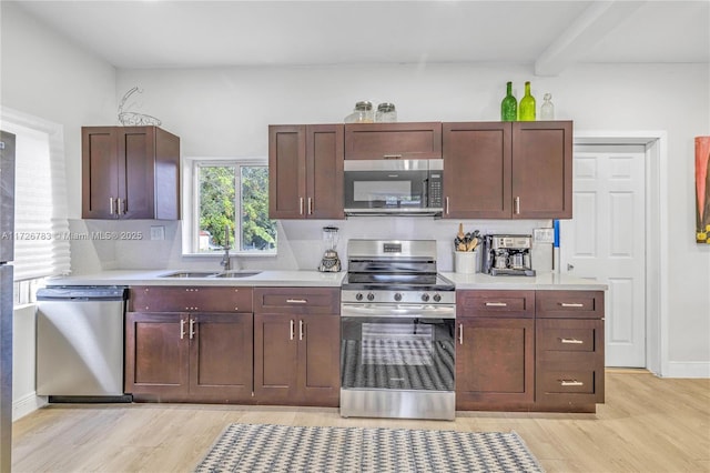 kitchen featuring stainless steel appliances, light hardwood / wood-style floors, backsplash, beamed ceiling, and sink