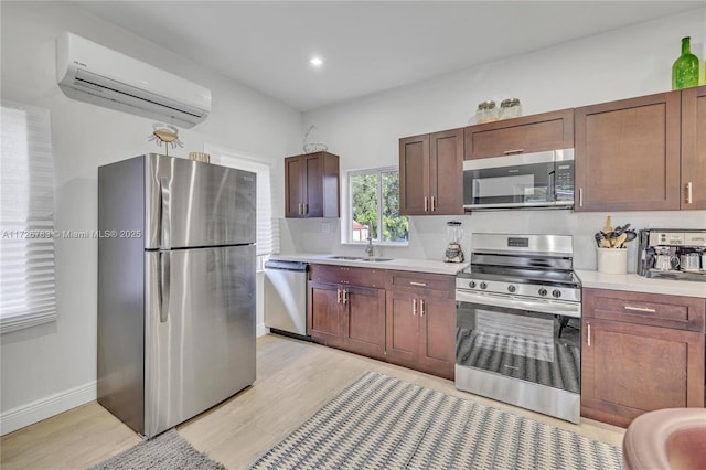 kitchen with stainless steel appliances, sink, light wood-type flooring, and a wall mounted air conditioner