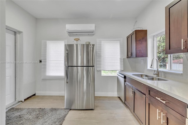 kitchen featuring sink, stainless steel appliances, a healthy amount of sunlight, and an AC wall unit