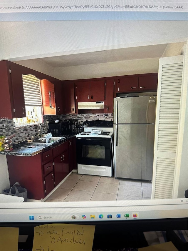 kitchen with electric range, stainless steel fridge, light tile patterned flooring, sink, and backsplash