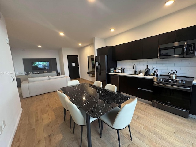 kitchen with light hardwood / wood-style floors, stainless steel appliances, sink, and decorative backsplash