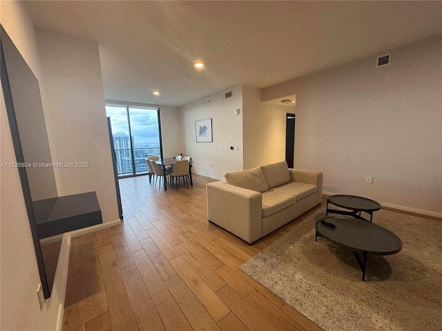 living room featuring a wall of windows and light hardwood / wood-style floors