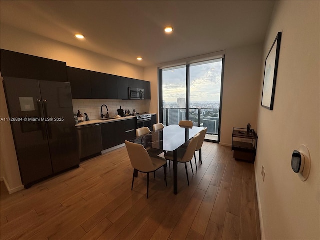 dining area featuring floor to ceiling windows, light hardwood / wood-style flooring, and sink