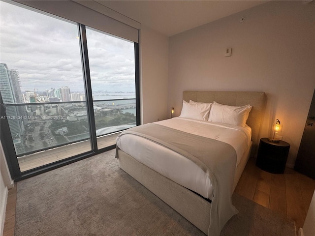 bedroom with access to outside, hardwood / wood-style floors, and multiple windows