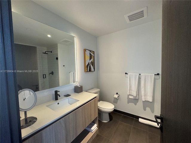 bathroom with tiled shower, tile patterned flooring, vanity, and toilet