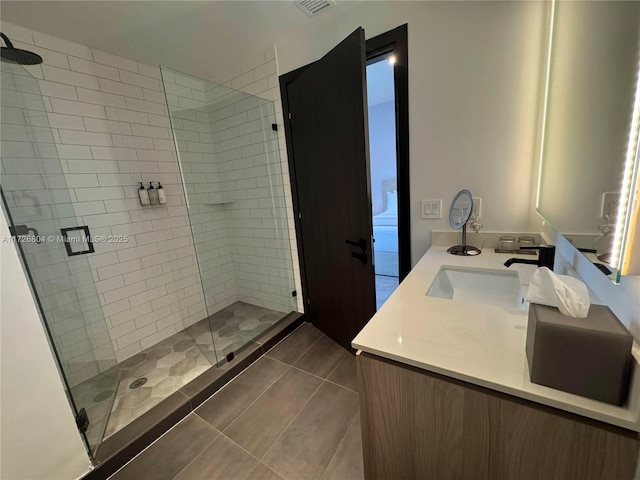 bathroom with a shower with door, vanity, and tile patterned floors