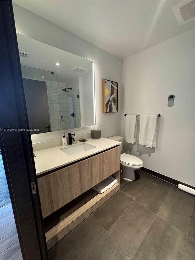 bathroom featuring a tile shower, vanity, and toilet