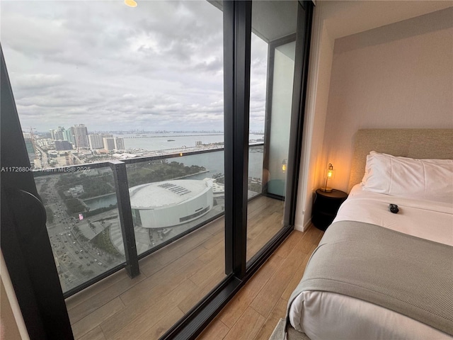 bedroom featuring a wall of windows, wood-type flooring, and a water view