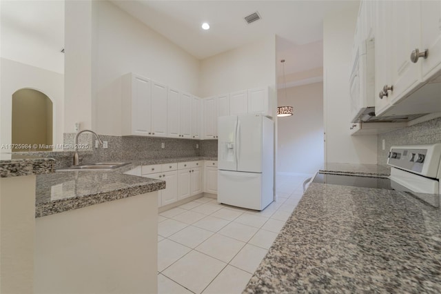 kitchen featuring white appliances, a towering ceiling, light tile patterned floors, sink, and white cabinetry