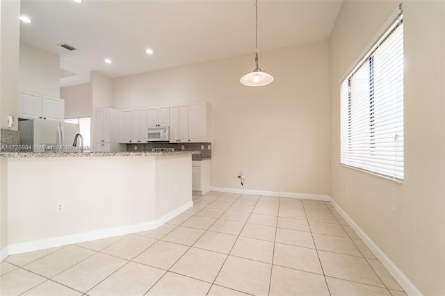 kitchen featuring white appliances, white cabinetry, and kitchen peninsula