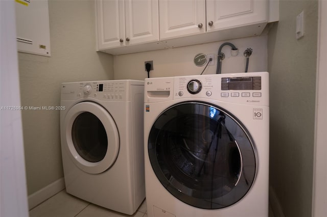 clothes washing area with separate washer and dryer, cabinets, and light tile patterned floors