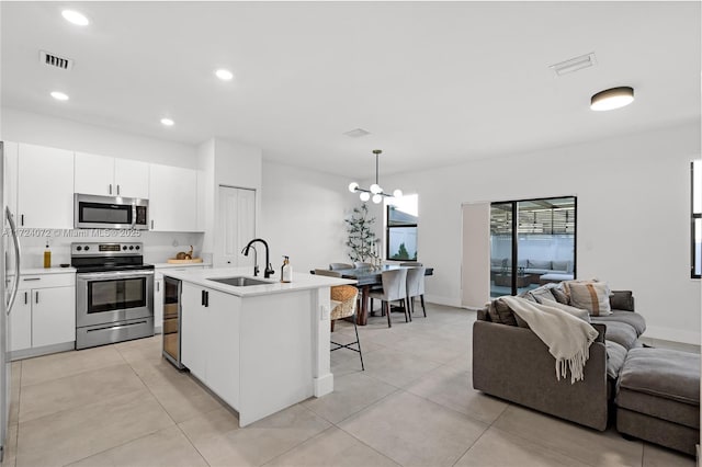 kitchen featuring stainless steel appliances, white cabinetry, hanging light fixtures, and sink