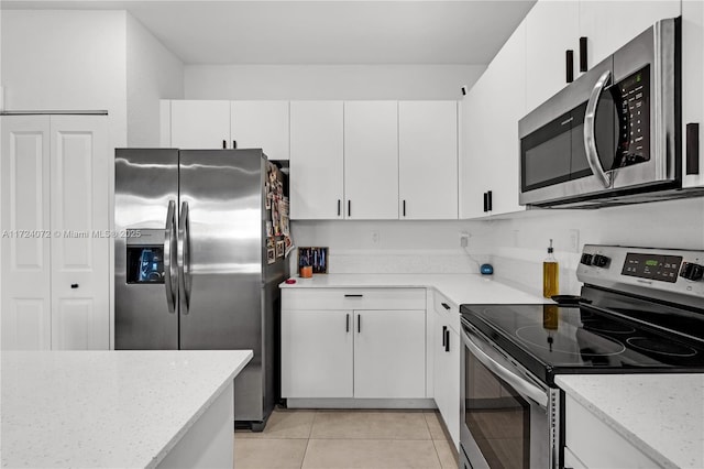 kitchen featuring white cabinets, appliances with stainless steel finishes, light tile patterned floors, and light stone counters