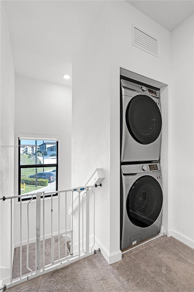 laundry room with carpet floors and stacked washer and clothes dryer